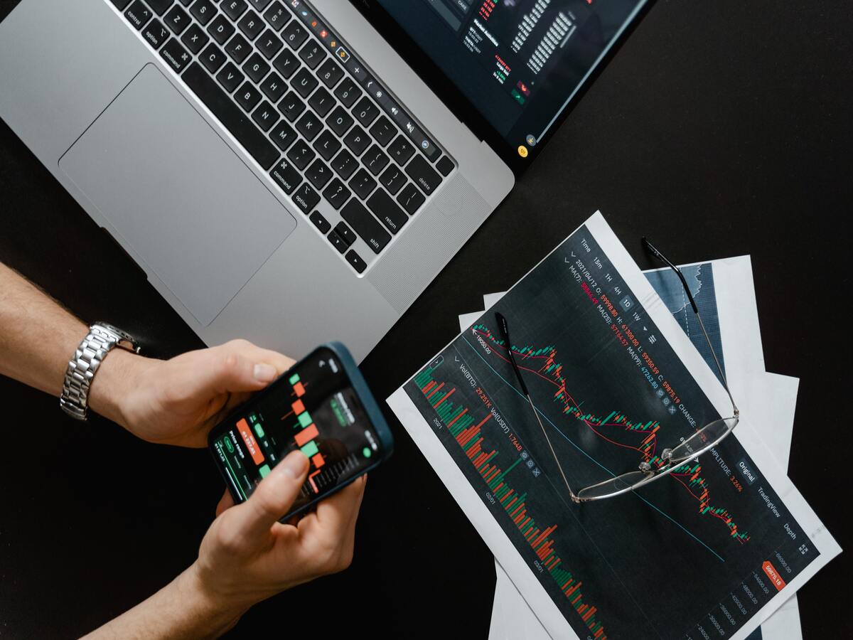 human hands holding a mobile phone showing a investment trend chart