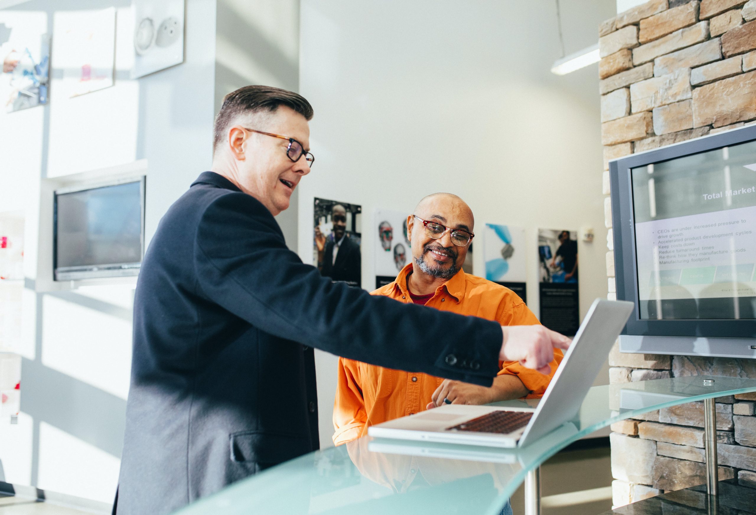 two men discussing in front of a laptop