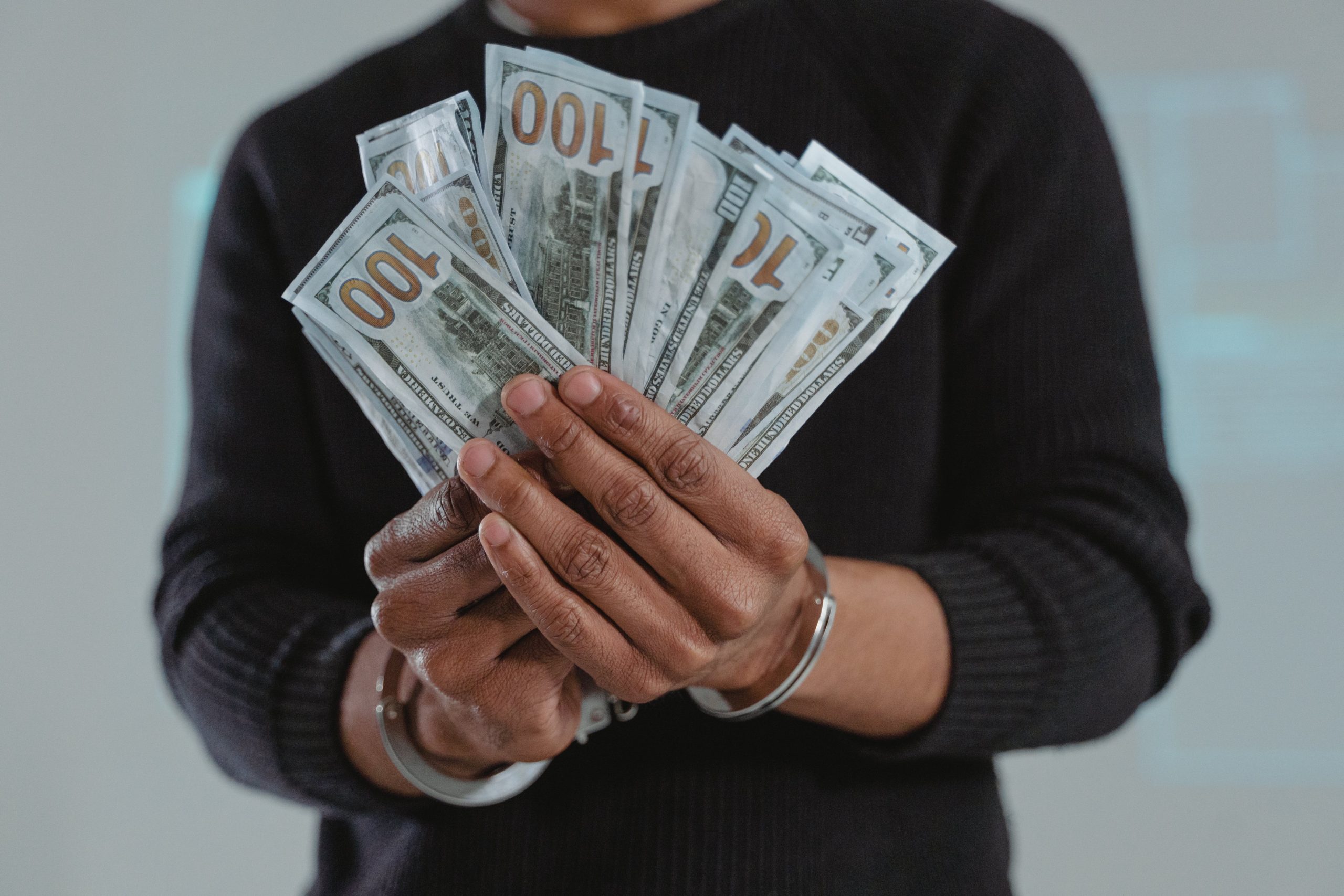 a man holding money with his hand being handcuffed